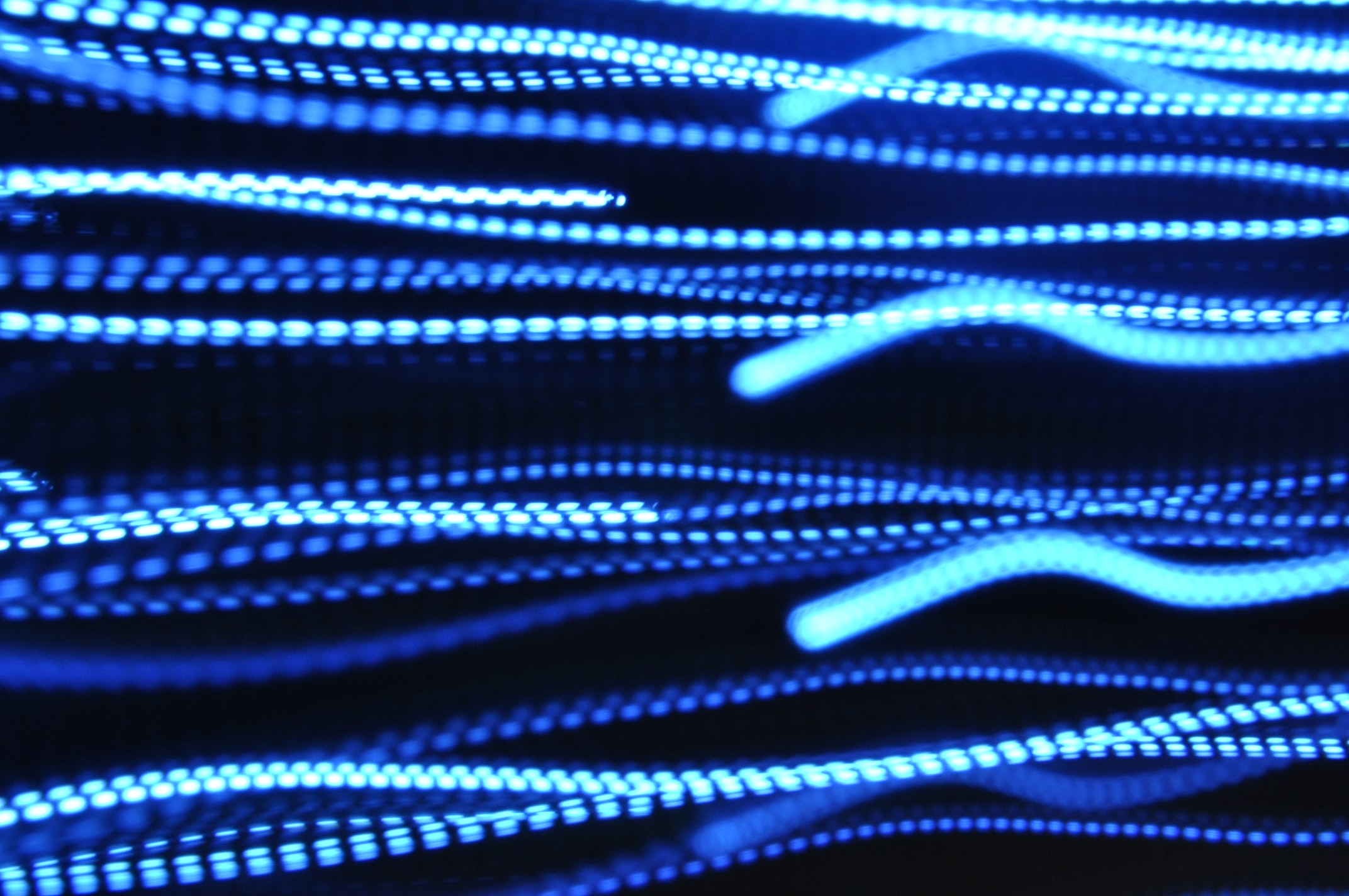 Câbles néon bleus ondulés du réseaux informatique de l'agence digitale à Reims et Paris
